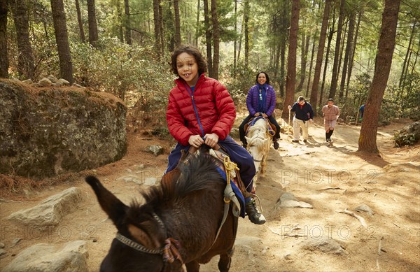 Mixed Race mother and son riding horses