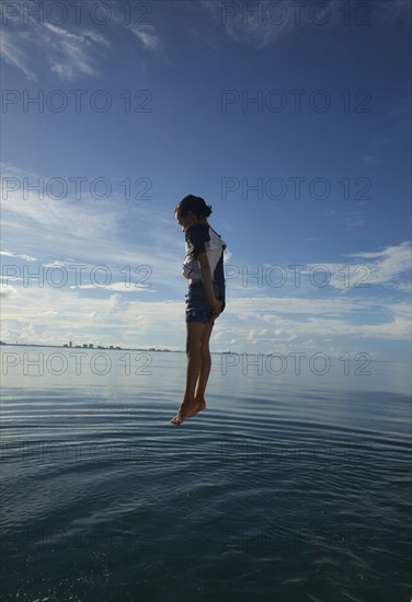 Mixed Race boy jumping into ocean