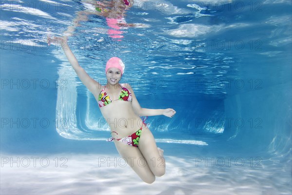 Hispanic woman in bikini swimming underwater