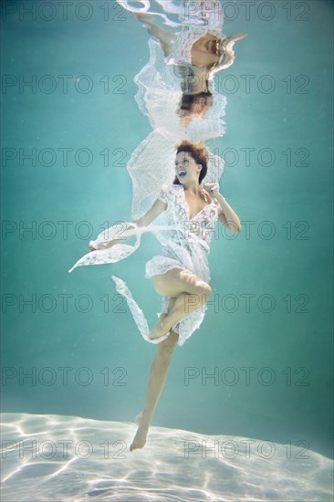 Caucasian woman in elegant dress under water