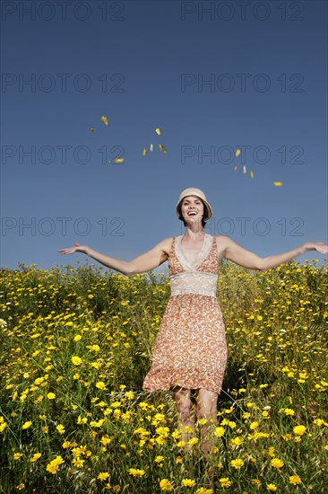 Caucasian woman throwing wildflowers in field