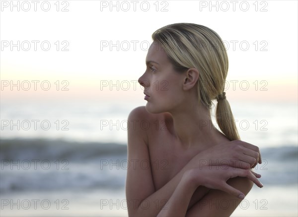 Topless Caucasian woman standing on beach