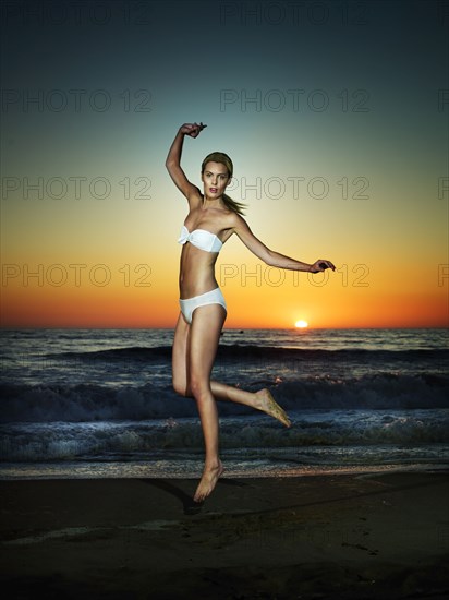 Caucasian woman jumping on beach