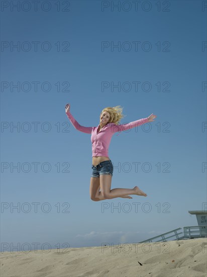 Caucasian woman jumping on beach