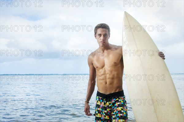 Caucasian man holding surfboard near ocean