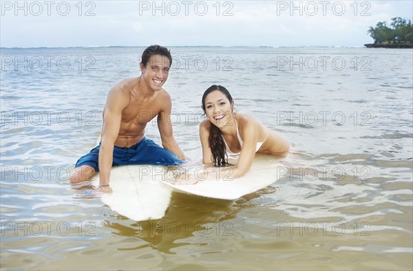Couple floating in ocean on surfboards