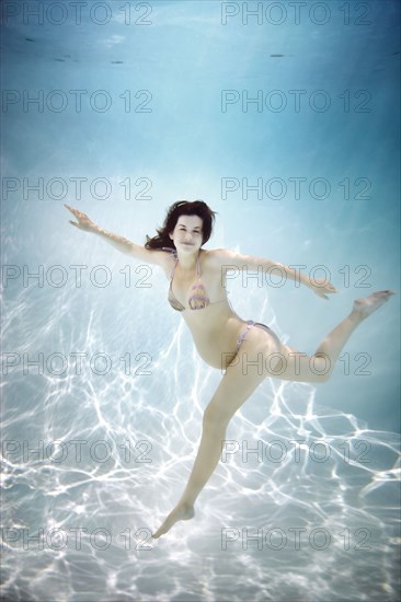 Pregnant Caucasian woman swimming underwater