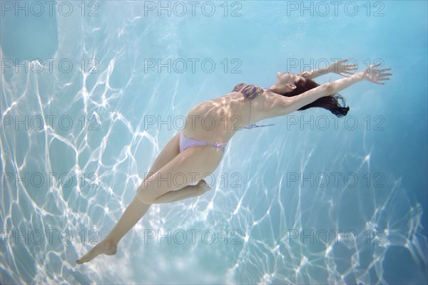 Pregnant Caucasian woman swimming underwater