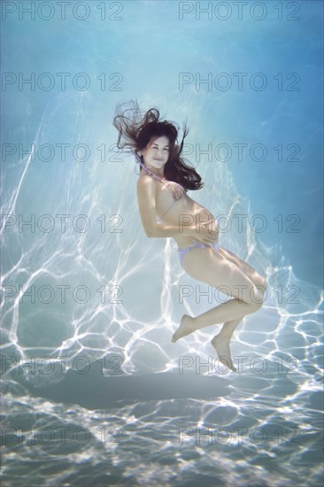 Pregnant Caucasian woman swimming underwater