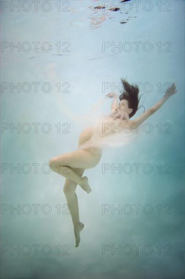 Pregnant Caucasian woman swimming underwater