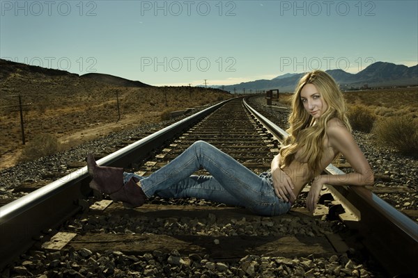 Caucasian woman laying on railroad tracks