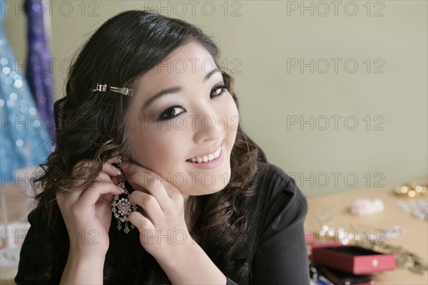 Mixed race woman putting on earrings