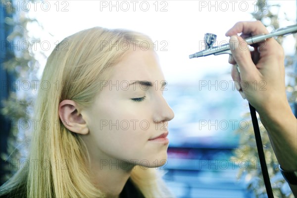 Woman having makeup spray painted on her face