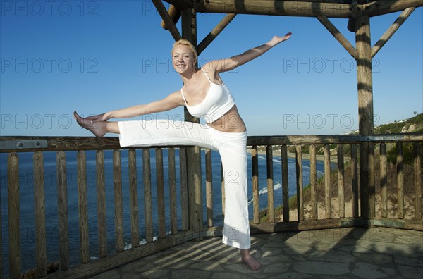 Caucasian woman practicing yoga near ocean