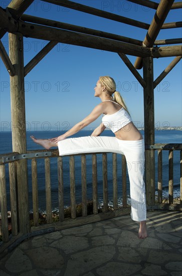 Caucasian woman practicing yoga near ocean