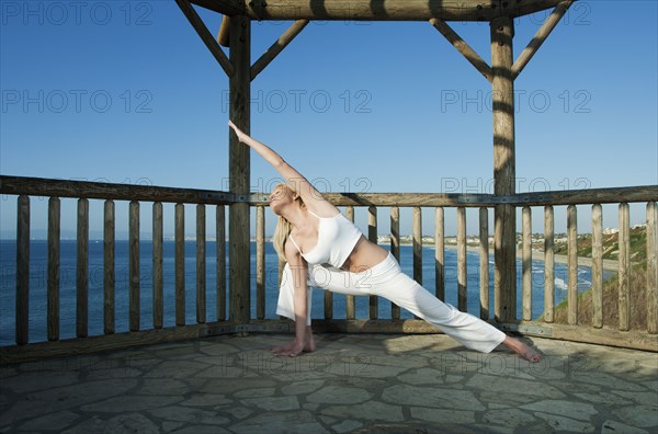 Caucasian woman practicing yoga near ocean