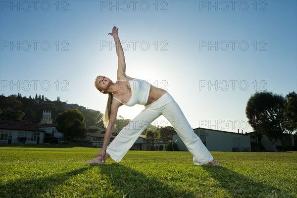 Caucasian woman practicing yoga in field