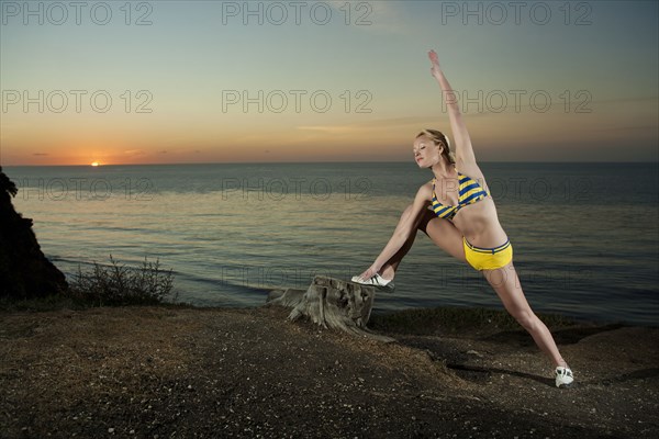 Caucasian woman stretching near ocean