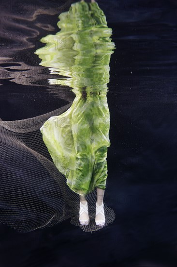 Mixed race woman in dress swimming under water