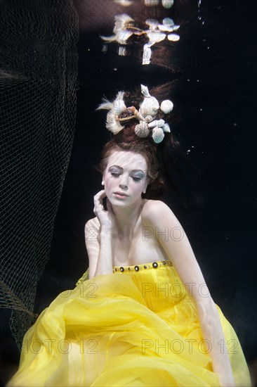 Mixed race woman in dress swimming under water