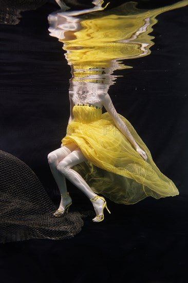 Mixed race woman in dress swimming under water