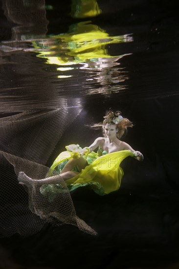 Caucasian woman in dress swimming under water