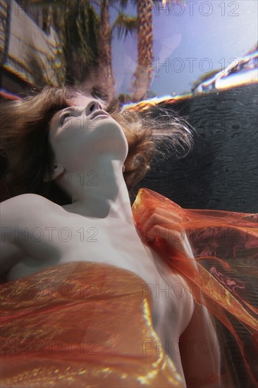 Caucasian woman in dress swimming under water