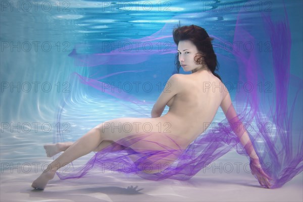 Caucasian woman in scarf swimming under water