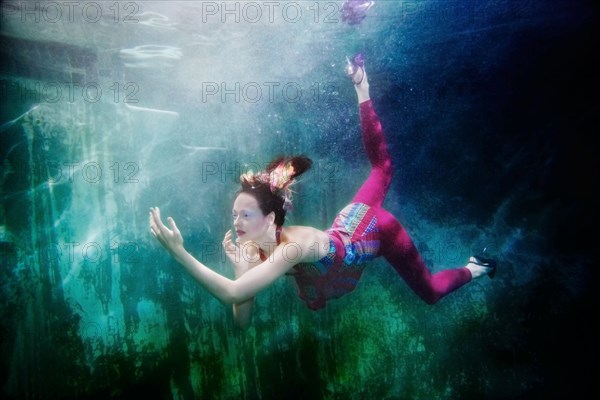 Caucasian woman in clothing swimming under water