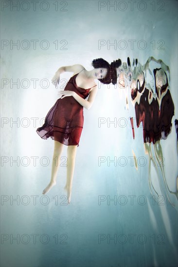 Caucasian woman in dress swimming under water