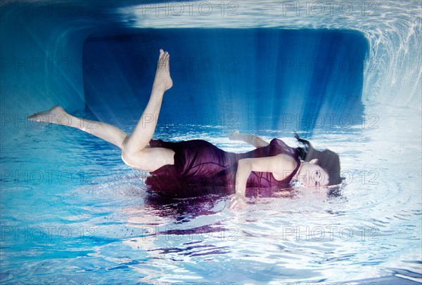 Hispanic woman in dress laying on top of water