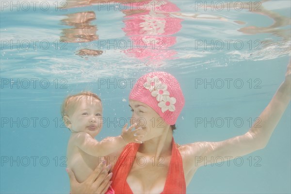 Caucasian mother holding baby underwater