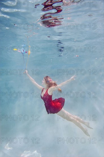 Caucasian woman with balloons underwater