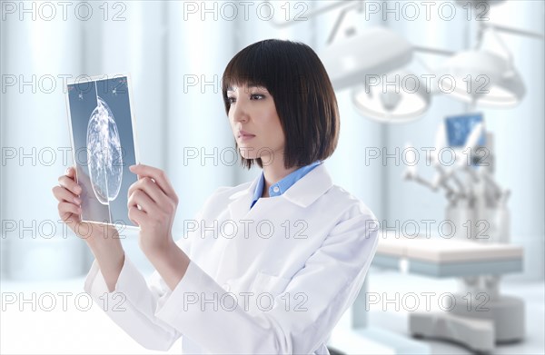 Mixed race doctor looking at digital tablet in operating room