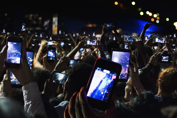 Crowd of people recording video with cell phones at night