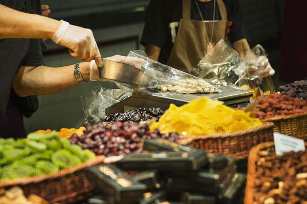 Worker scooping nuts into plastic bag at market