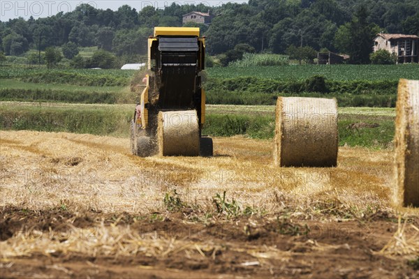 Tractor baling hay in field