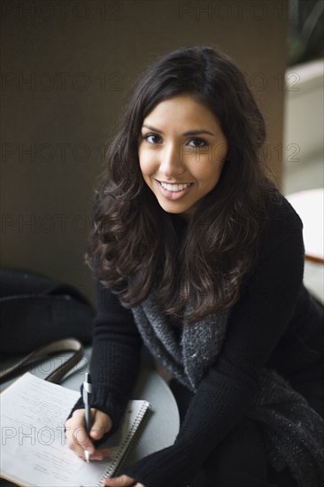 Middle Eastern woman writing in notebook