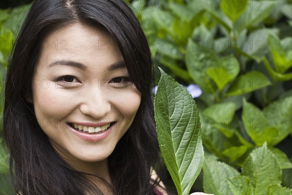 Smiling Japanese woman holding leaf