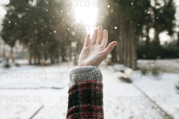 Hand of Caucasian woman catching falling snow