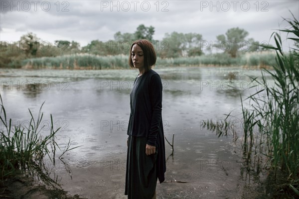 Caucasian woman standing near river in rain