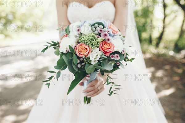 Caucasian bride holding bouquet of flowers outdoors