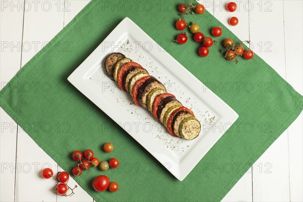Plate of sliced food and tomatoes on plate and green linen