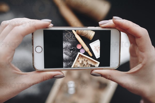 Hands of Caucasian woman photographing baking supplies