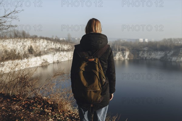 Caucasian woman standing at the edge of reservoir wearing backpack