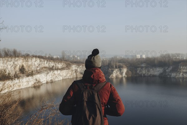 Caucasian man at the edge of reservoir wearing backpack