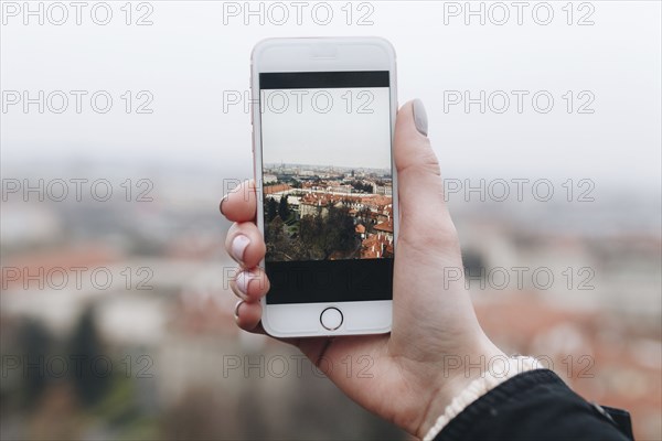 Hand of Caucasian woman photographing cityscape with cell phone