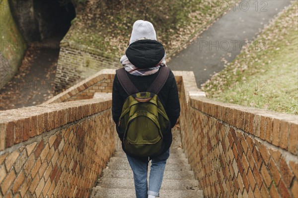 Caucasian woman carrying backpack descending staircase outdoors