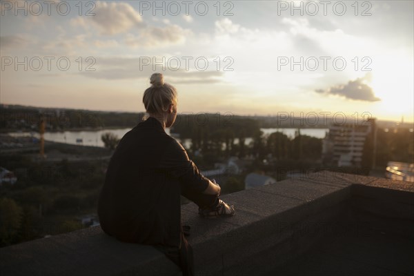 Caucasian woman on roof admiring scenic view of sunset