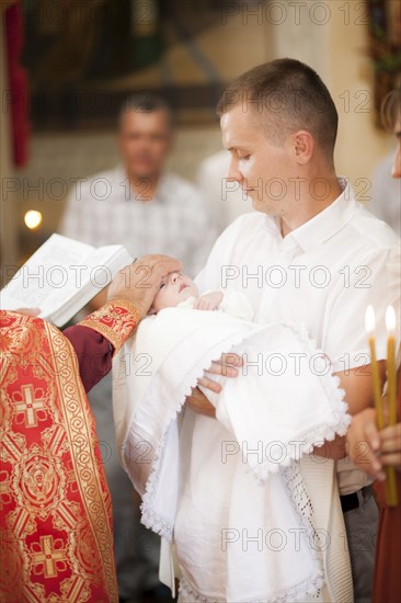 Priest blessing baby boy in church